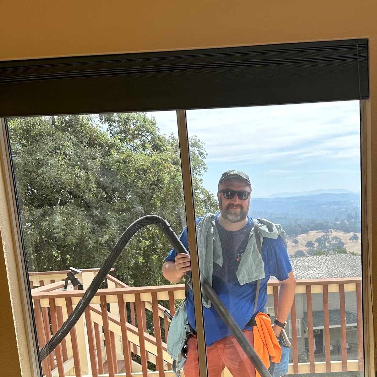 Smiling technician seen through freshly cleaned glass with foothill views behind