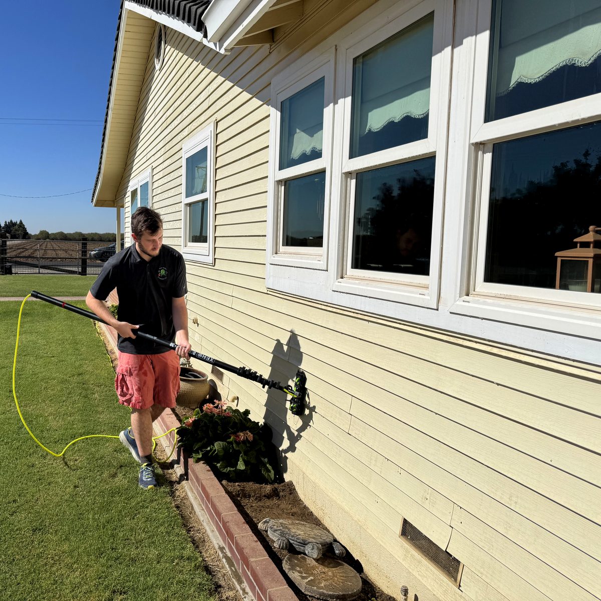 Technician cleaning exterior windows of a ranch home near Sonora