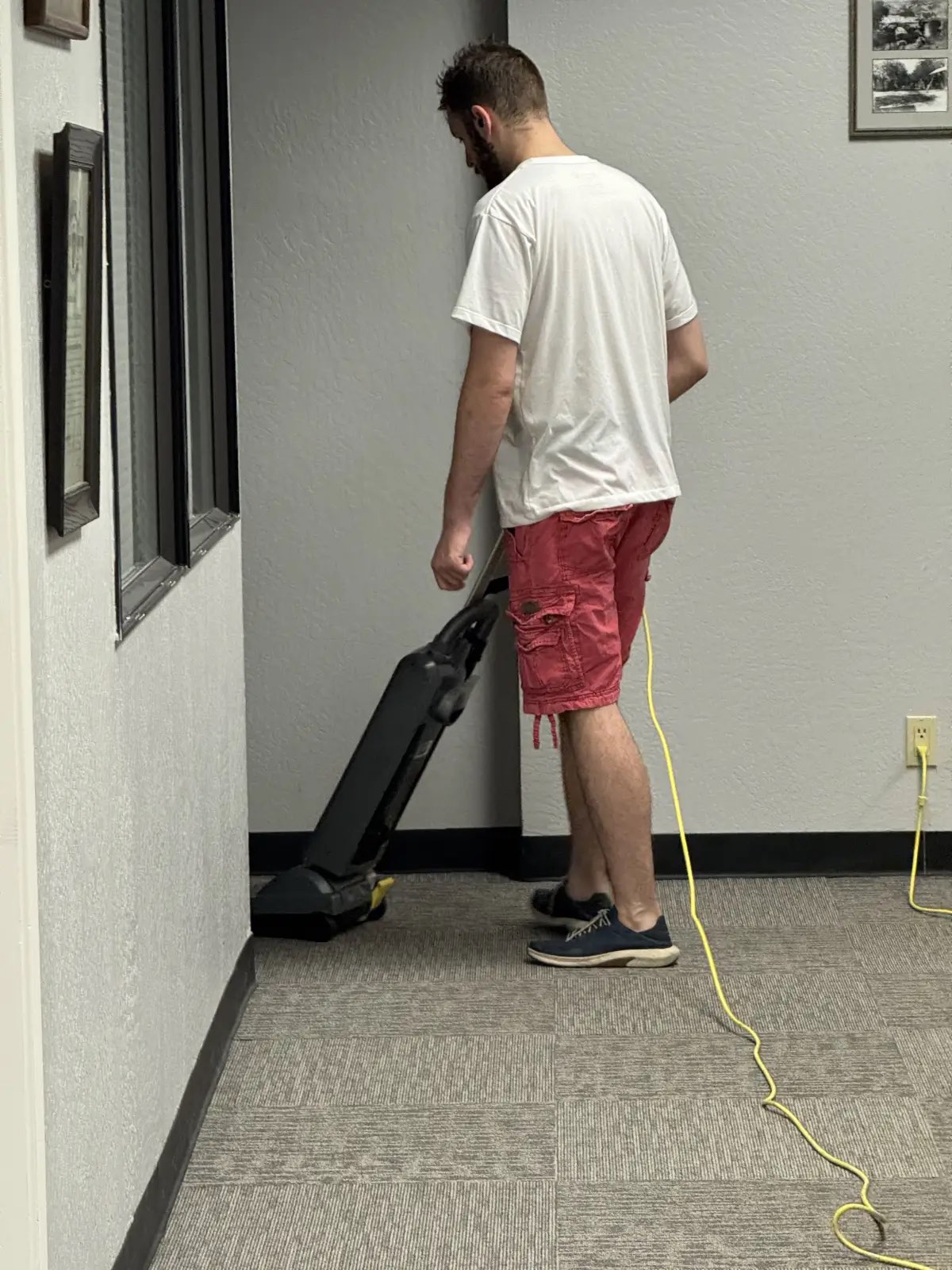 Technician vacuuming carpet in a Sonora-area office corridor